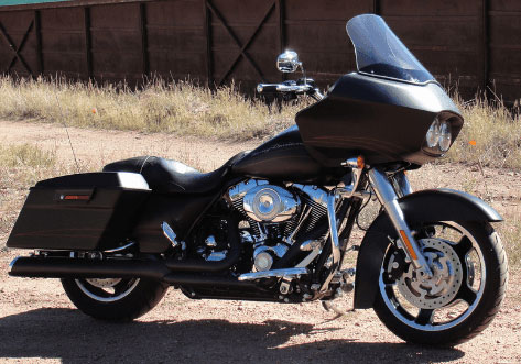BLACK MOTORCYCLE WITH LONG SHADOW PARKED ON GRAVEL